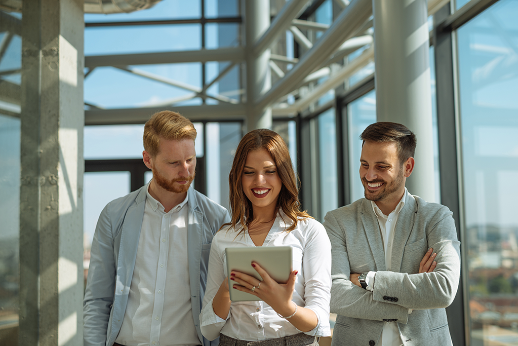 Three business workers looking over an ipad 